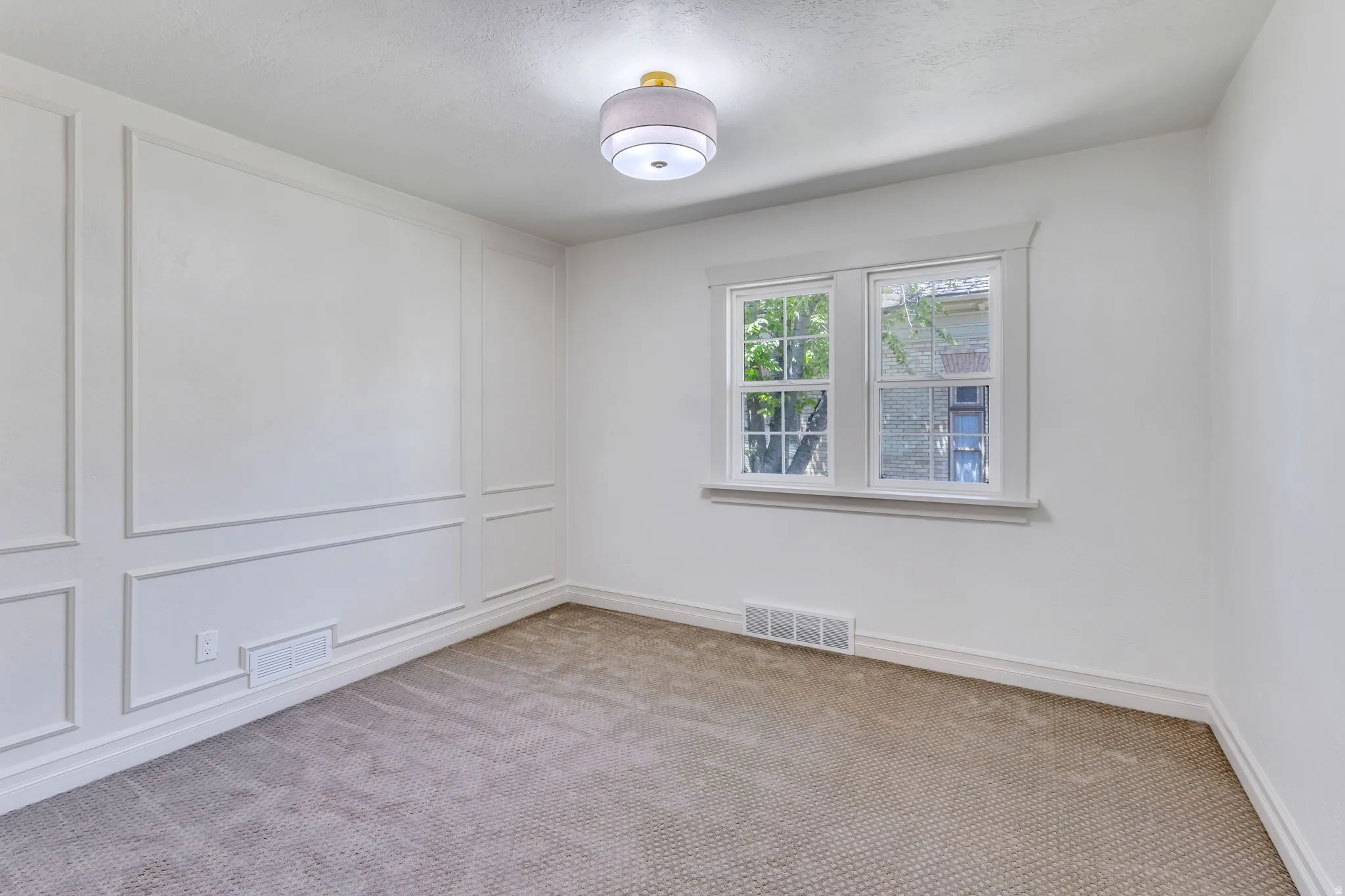 Room featuring a textured carpet, decorative wall paneling, and a contemporary flush mount light fixture