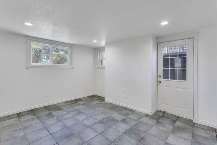 Room featuring square tile flooring, white walls, recessed lighting, and a white paneled door with glass inserts