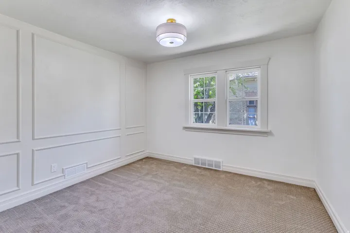 Room featuring a textured carpet, decorative wall paneling, and a contemporary flush mount light fixture