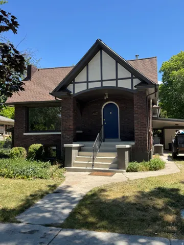 Brick facade home featuring a Tudor-style gabled dormer with dark trim and white panels
