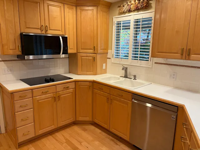 Kitchen featuring wood cabinetry, white countertops, built-in microwave, stainless steel dishwasher, and a double basin sink