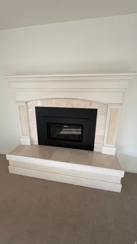 Fireplace featuring a classic white mantel, tiled surround, and integrated firebox with a black metal frame