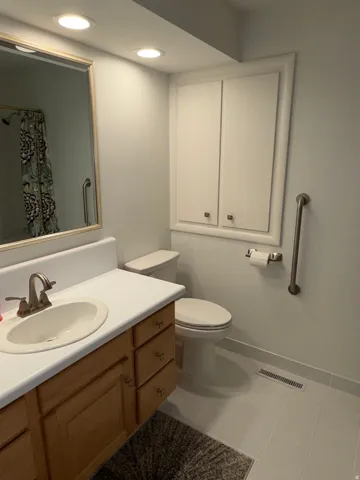Bathroom featuring a light wood-finish vanity with an integrated sink, white countertop, and a brushed nickel faucet