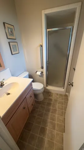 Bathroom featuring a tiled shower enclosure with a framed glass door, a toilet, and a vanity with an integrated sink