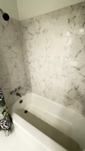 White bathtub with a chrome showerhead and control fixtures