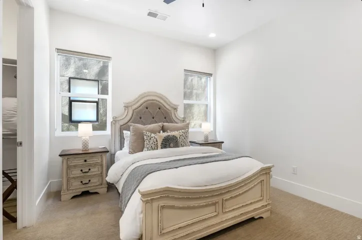 Carpeted bedroom featuring recessed lighting, a ceiling mounted light fixture, and two windows with window treatments