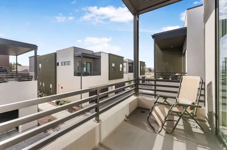 Private balcony featuring a concrete floor, metal railing, and an overhead structure
