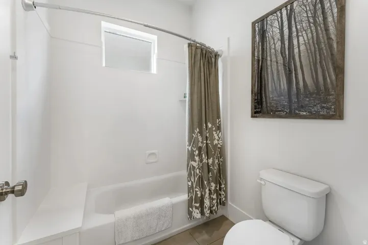 Bathroom featuring a white bathtub, white toilet, and a window above the tub