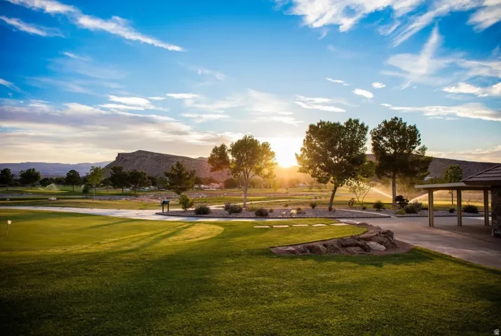 Expansive golf course property featuring manicured greens, a paved cart path, and a putting green with flag