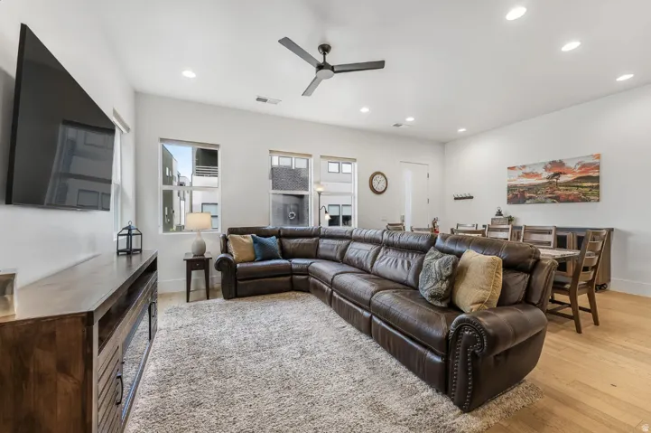 Open-concept living area with light wood-finish flooring and recessed lighting