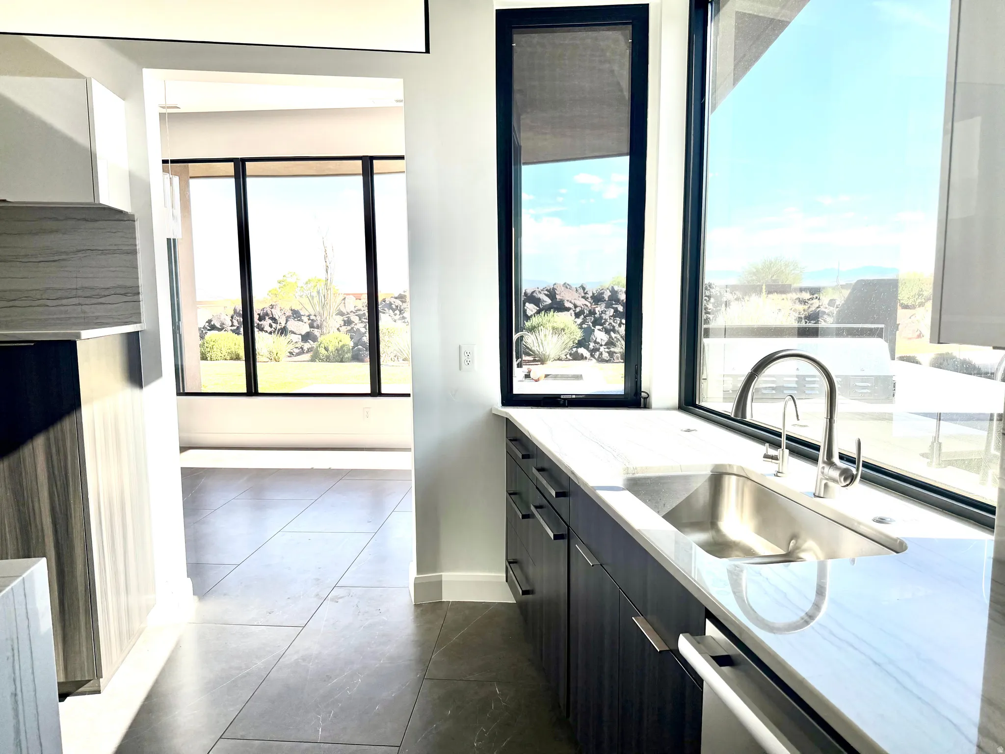 Kitchen sink area featuring an undermount stainless steel sink, a gooseneck faucet, and light-toned countertops
