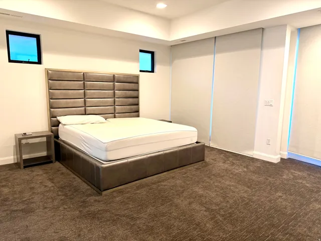 Spacious room featuring broadloom carpeting, two high transom windows, and full-height roller shades