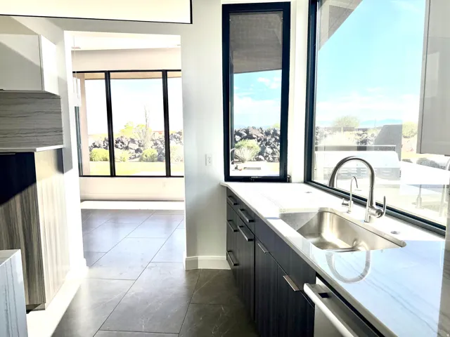 Kitchen sink area featuring an undermount stainless steel sink, a gooseneck faucet, and light-toned countertops
