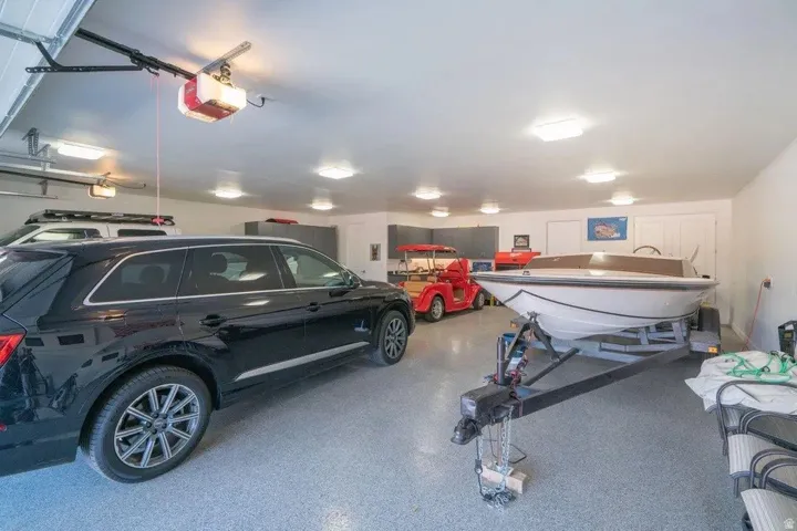 Spacious garage featuring an epoxy floor coating, multiple overhead light fixtures, and a white paneled door