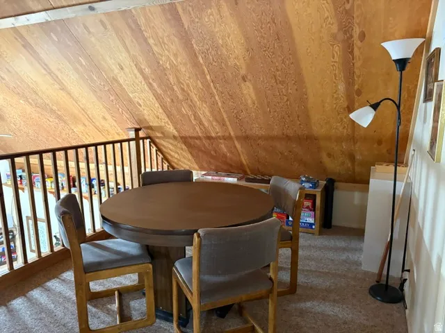 Loft common space featuring sloped wood-paneled ceilings, view to great room below and gaming table and chairs