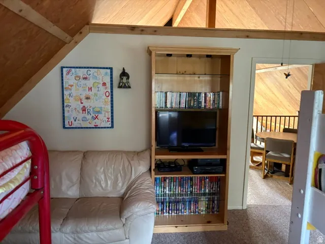 Loft bedroom with a sofa and bookcase looking out to loft common area gaming table