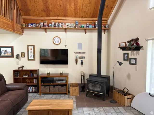 Living area with a wood-burning stove and tile hearth, wall-mounted TV and decorative wood shelving