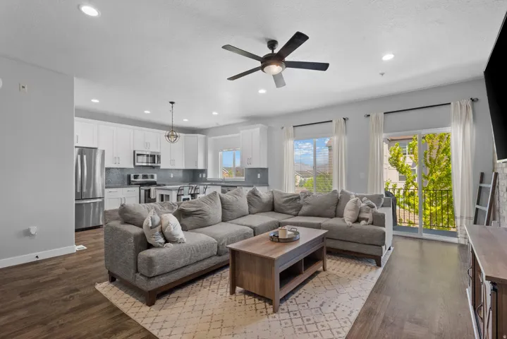 Open-concept living space featuring wood-finish flooring, recessed lighting, and a dark-toned ceiling fan