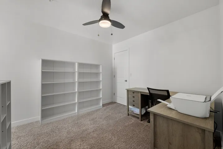 Room featuring wall-to-wall carpeting, white painted walls, and a ceiling fan with integrated lighting