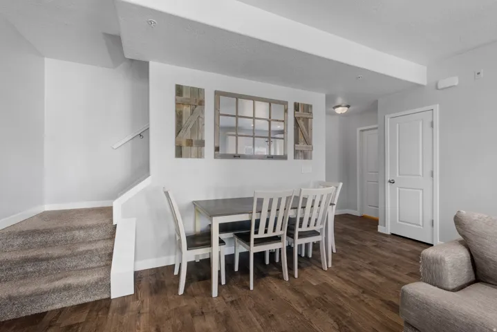 Open-concept living area featuring wood-finish flooring, light gray wall paint, and a carpeted staircase with a white handrail