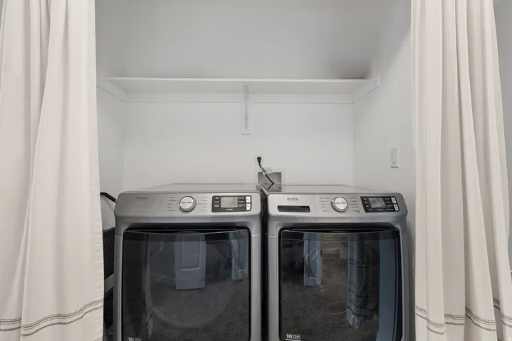Laundry area featuring a built-in shelf, white walls, and a recessed space for appliances