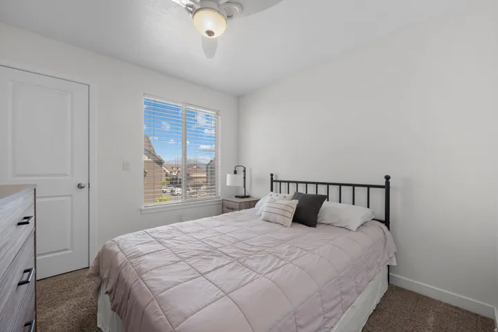 Bedroom featuring a window with horizontal blinds, overhead ceiling fan with lighting, light-toned walls, and carpet flooring
