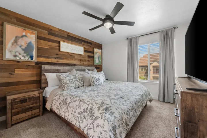 Bedroom featuring a wood-panel accent wall and a ceiling fan