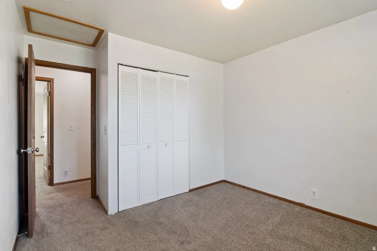 Carpeted room featuring white walls, a single ceiling light fixture, and a white louvered bifold closet door
