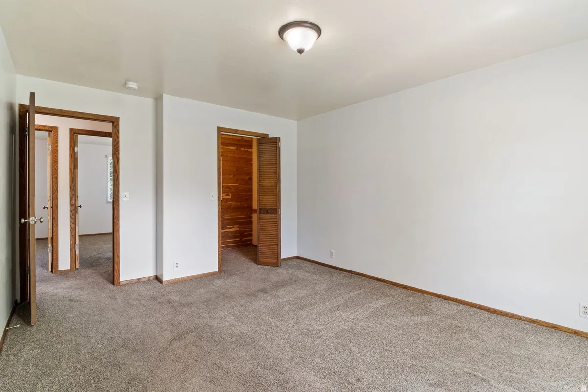 Neutral wall color with a semi-flush mount ceiling fixture, gray carpeting, and wood-finish trim
