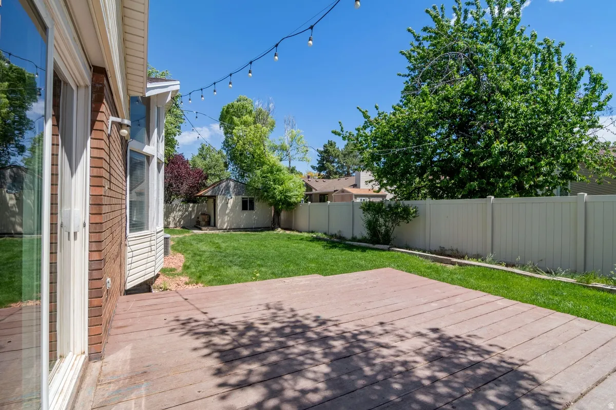 Expansive backyard featuring a wood-finish patio, manicured lawn, and a privacy fence