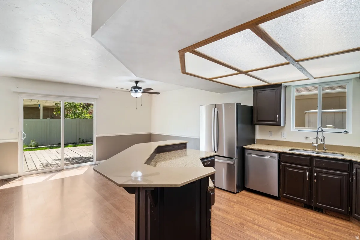 Kitchen and dining area featuring a breakfast bar with stone-finish countertop, dark wood-finish cabinetry, and stainless steel appliances