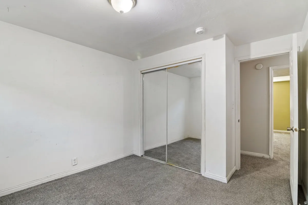 Carpeted room with a ceiling-mounted light fixture, mirrored closet doors, and white painted walls