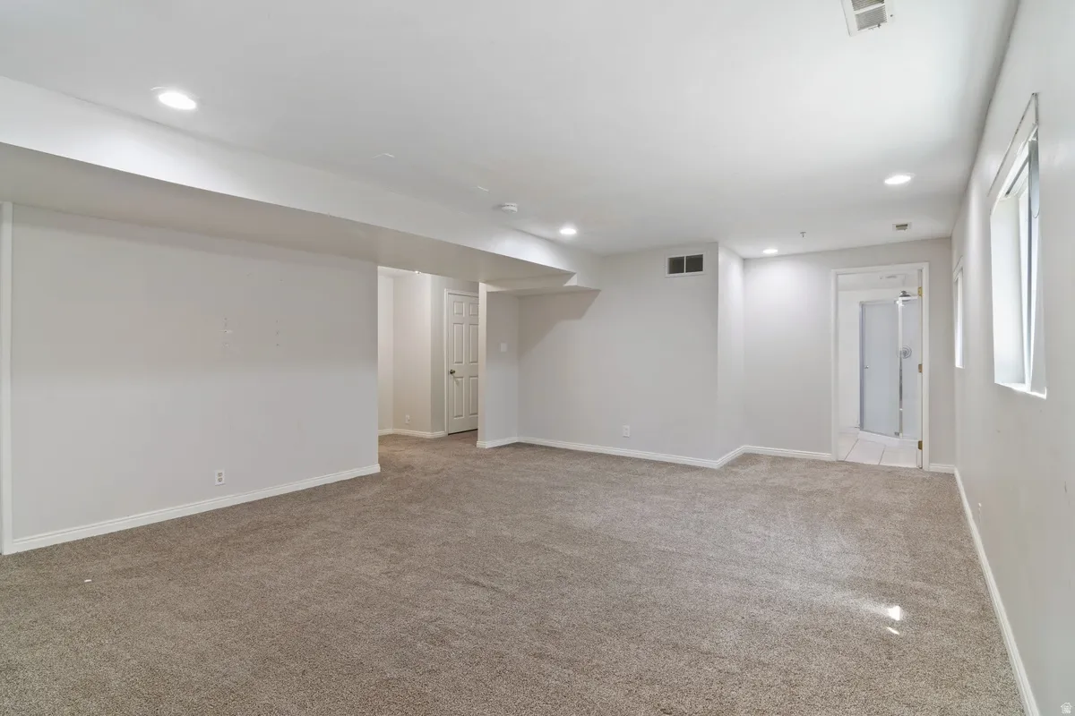 Spacious room featuring neutral carpeting, recessed lighting, white baseboards, and light-colored walls