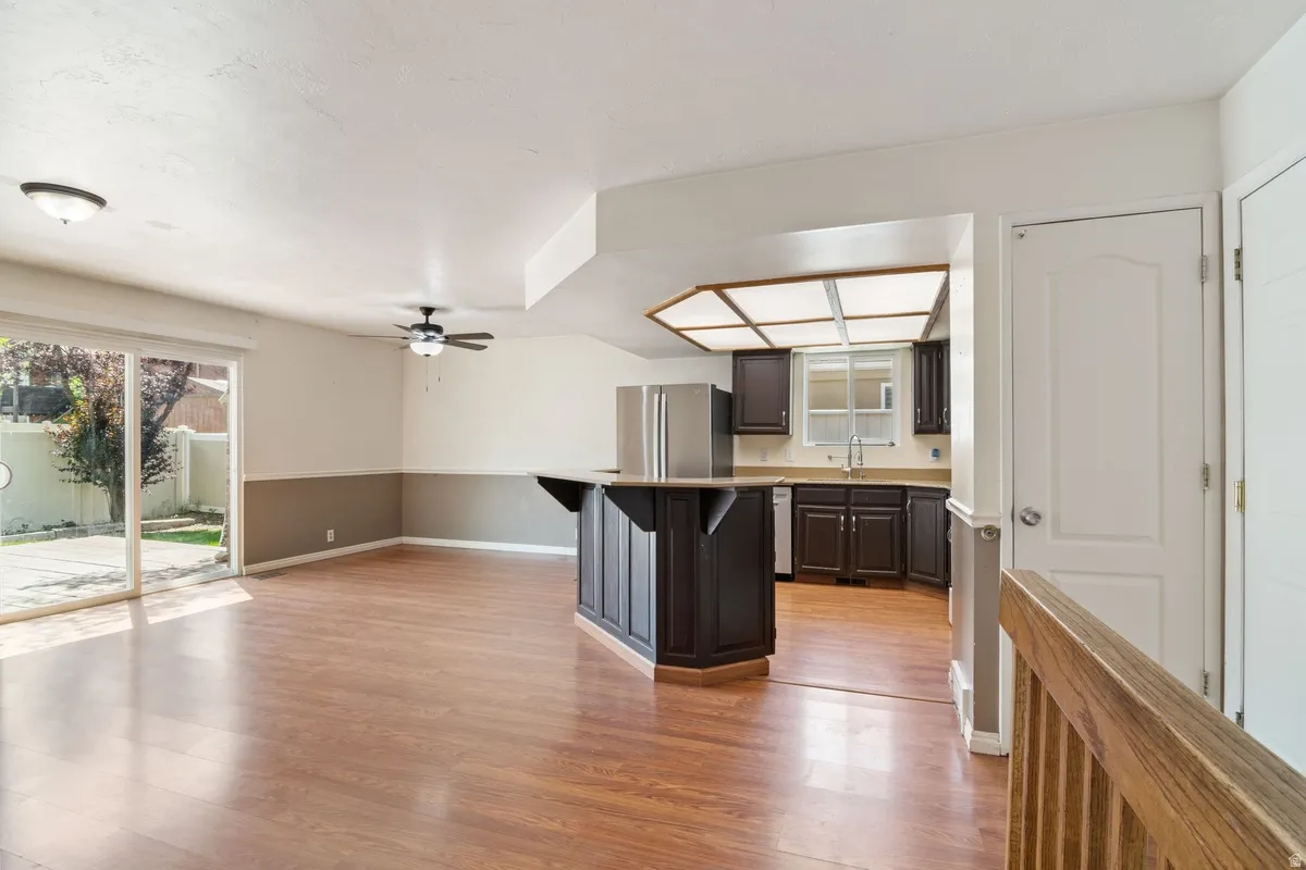 Open-concept living space featuring wood-finish flooring, a ceiling fan, and sliding glass doors to the exterior
