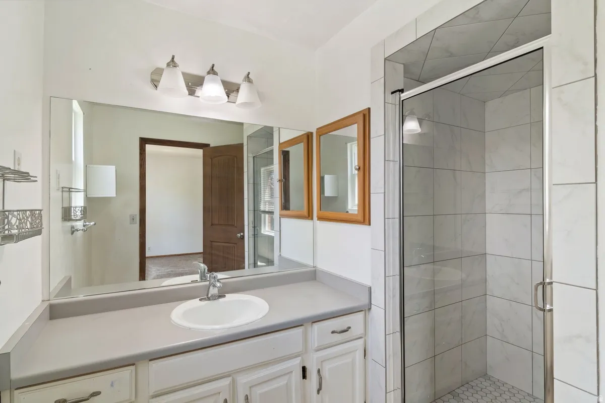 Modern bathroom featuring a single vanity with a white basin and chrome faucet, a large wall-mounted mirror, and a three-light vanity fixture