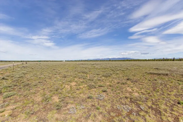 Expansive land offering a wide-open panorama, featuring natural vegetation and a distant mountain range under a broad sky