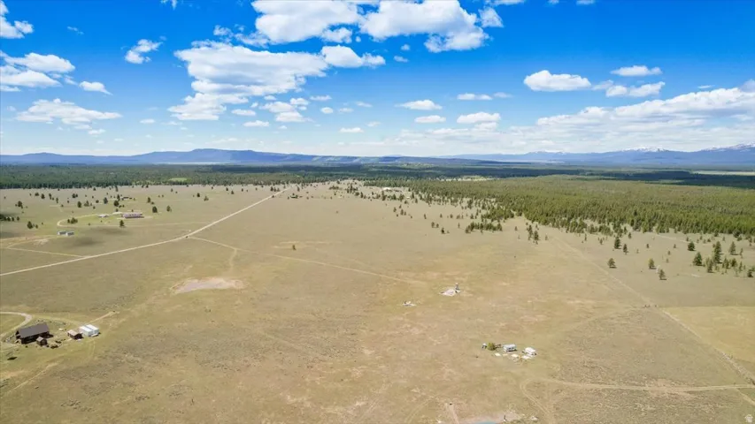 Expansive open land featuring distant mountain ranges and a tree line