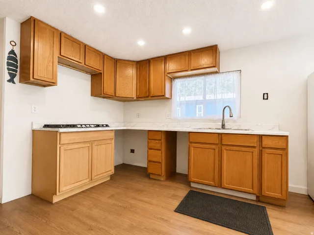 Kitchen featuring wood-finish flooring, recessed lighting, wood cabinetry, stone countertops, and a built-in gas cooktop