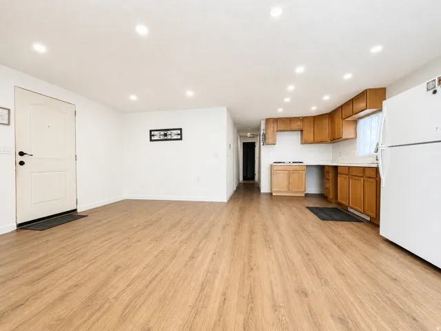 Open concept living area featuring wood-finish flooring, recessed lighting, and a white entry door