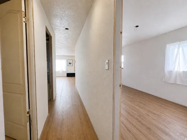 Hallway featuring wood-finish flooring, white walls, and a textured ceiling