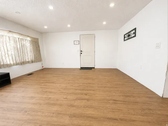 Spacious room featuring wood-finish flooring and recessed ceiling lighting