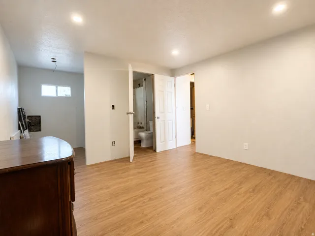 Spacious interior room with wood-finish flooring, recessed lighting, and light-toned wall finishes