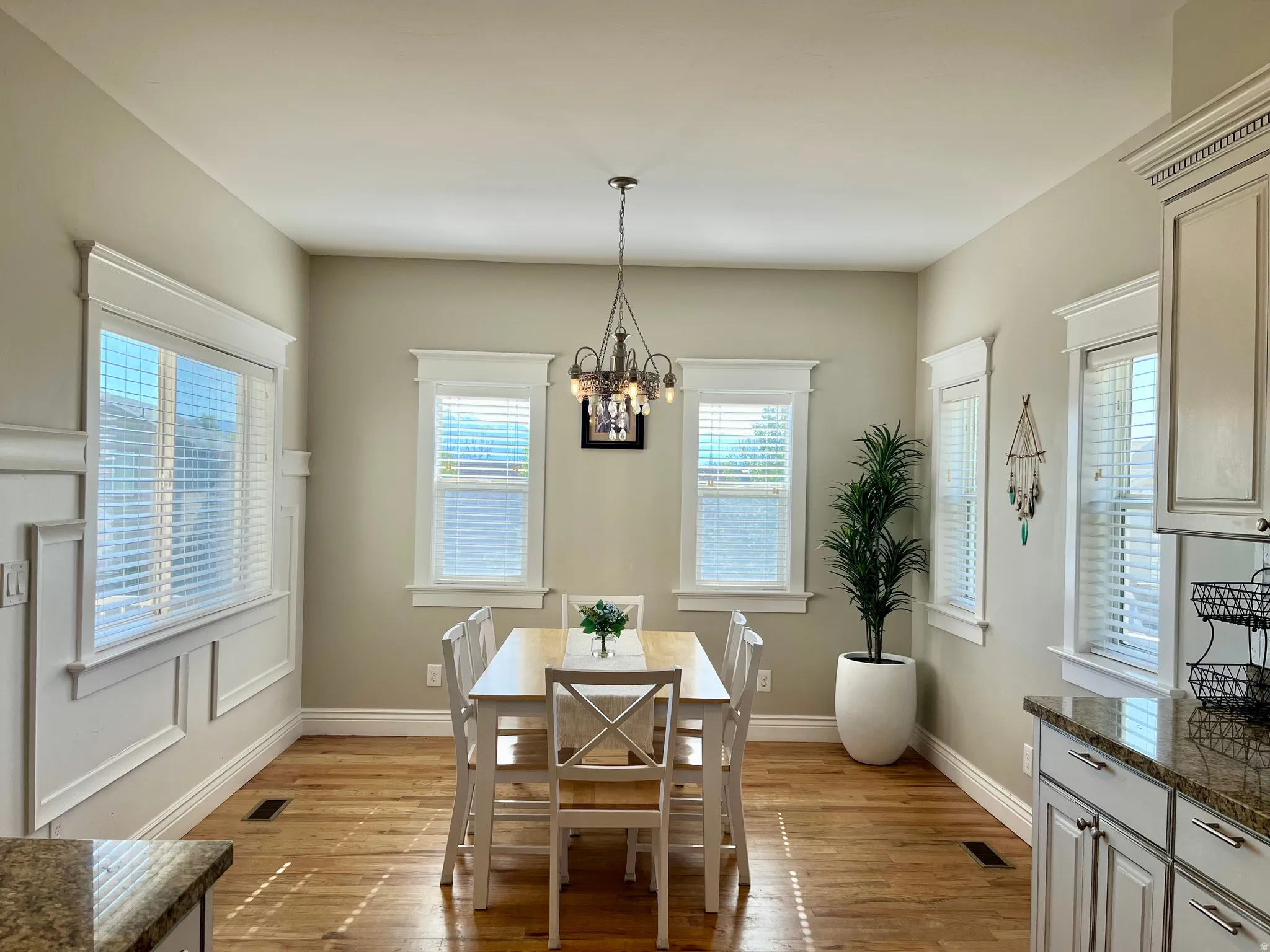 Dining area featuring wood-finish flooring, white window blinds, and an ornate chandelier