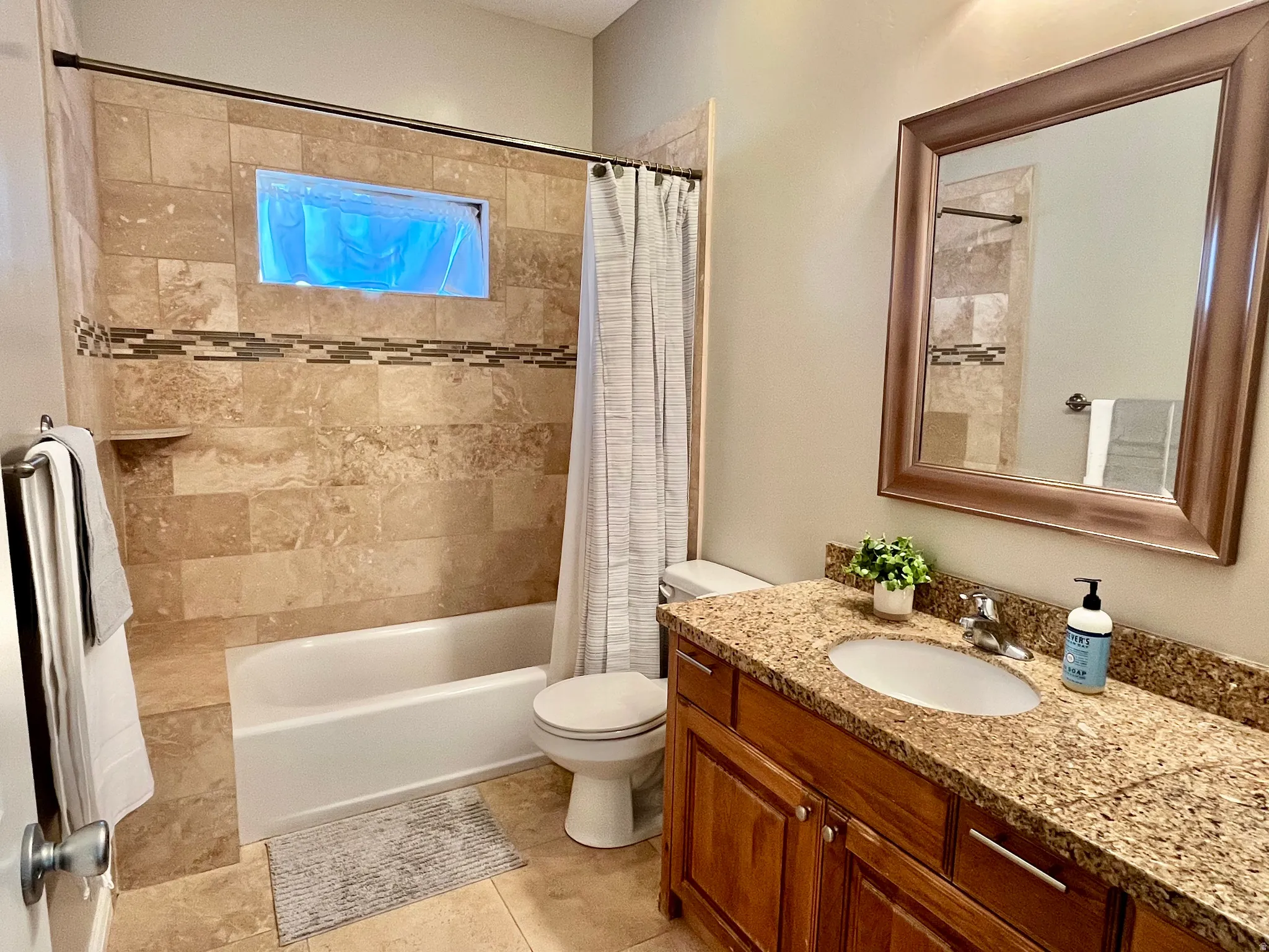 Bathroom featuring a tiled shower surround with an accent band, a built-in shower niche, and a coordinating tiled floor