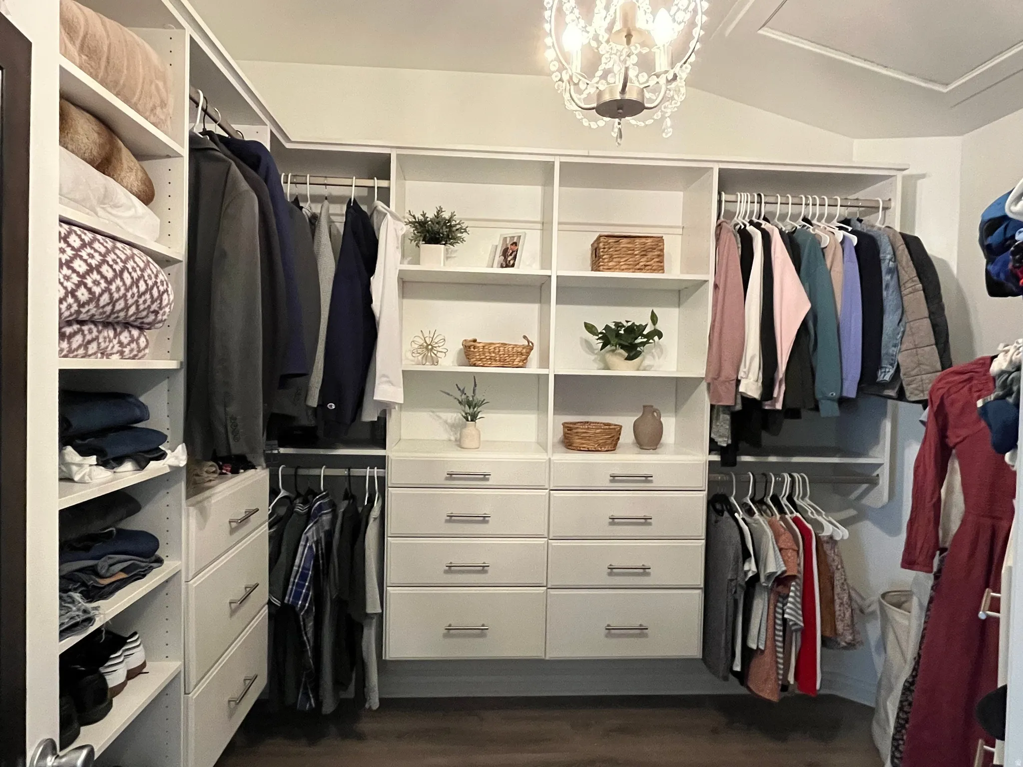 Custom closet system featuring white cabinetry, multiple hanging rods, and integrated shelving