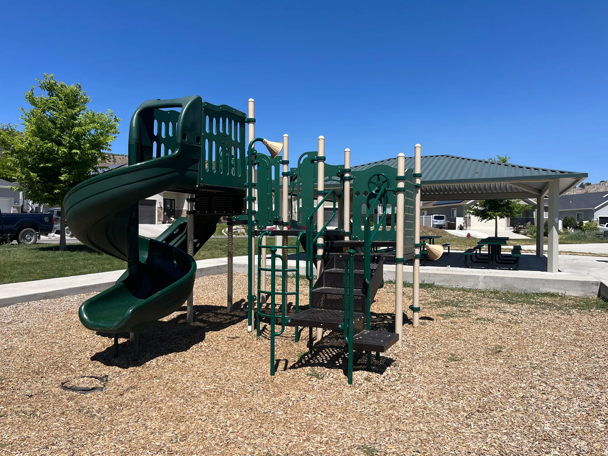 On-site playground featuring a spiral slide, climbing elements, and a protective wood chip surface