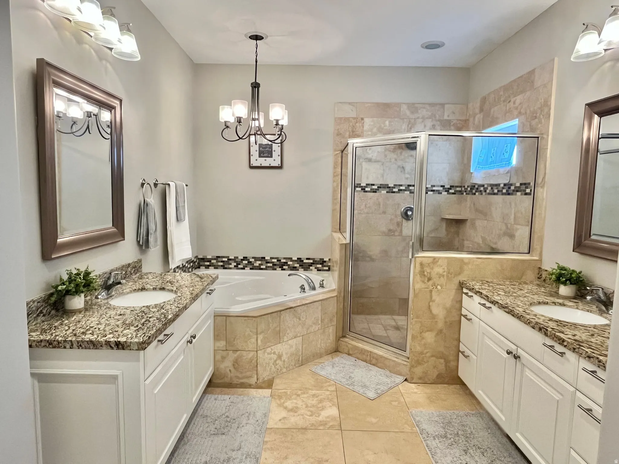 Bathroom featuring dual vanities with granite countertops and white cabinetry
