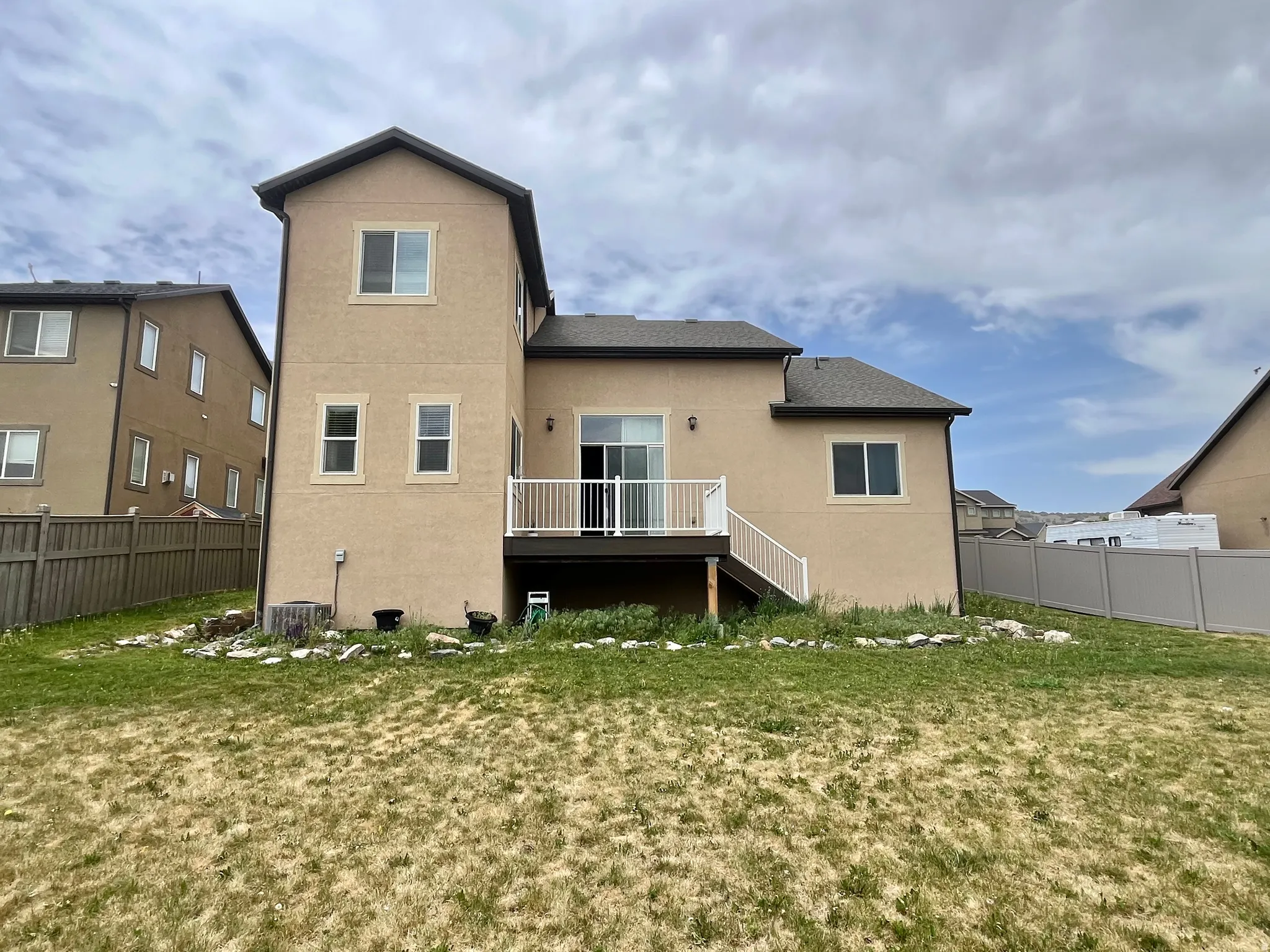 Two-story stucco exterior featuring a rear deck with white railings and a sliding glass door