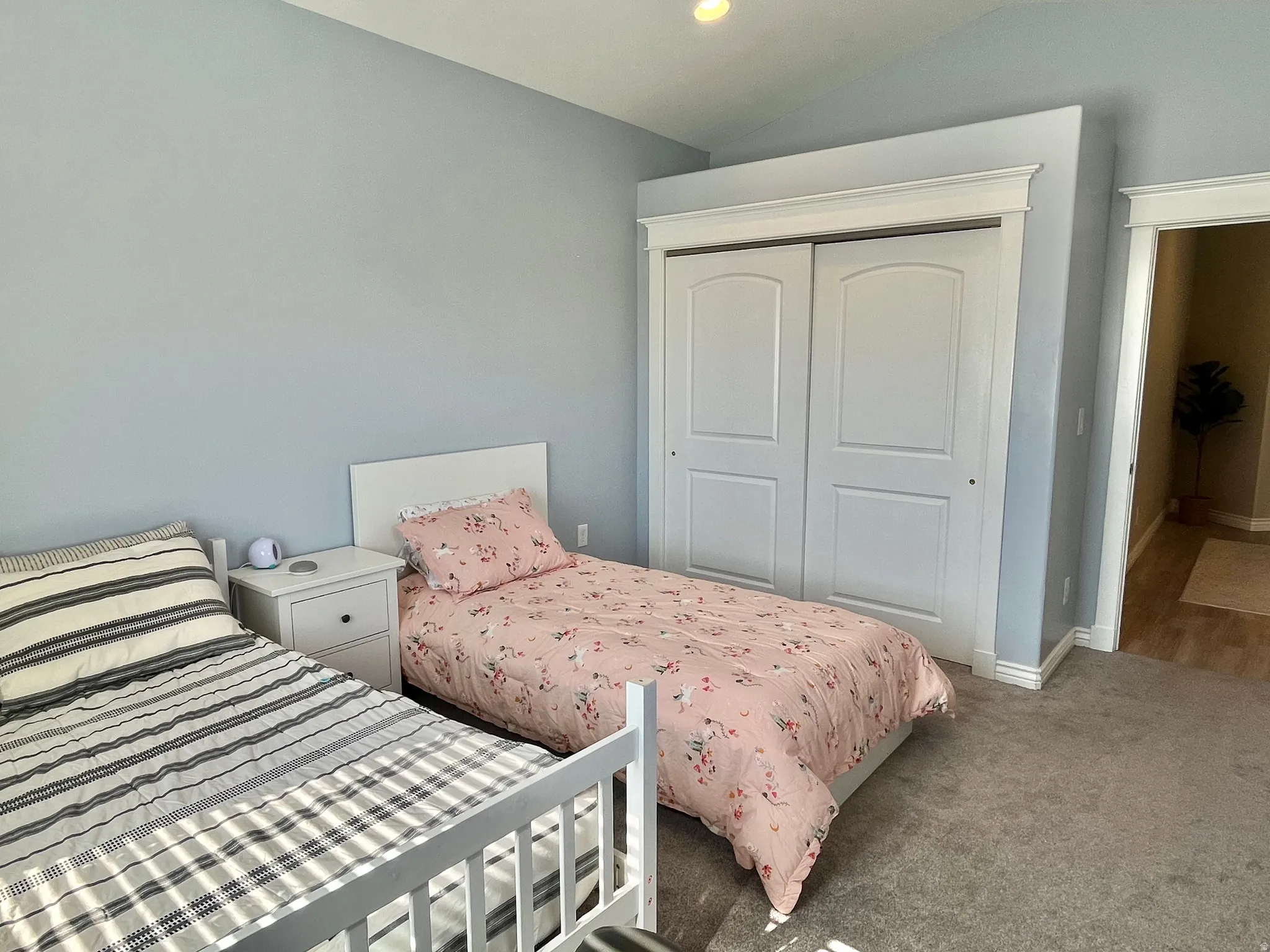 Light blue walls complement the gray carpeting in this room featuring a double-door closet with white trim
