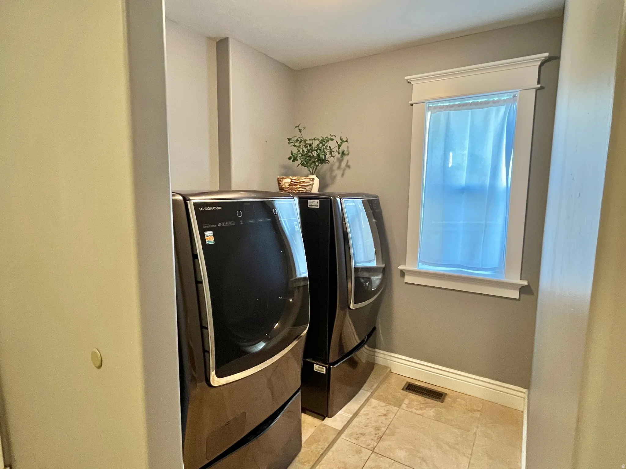 Laundry area featuring tile flooring, a window with trim, baseboard molding, and neutral wall paint
